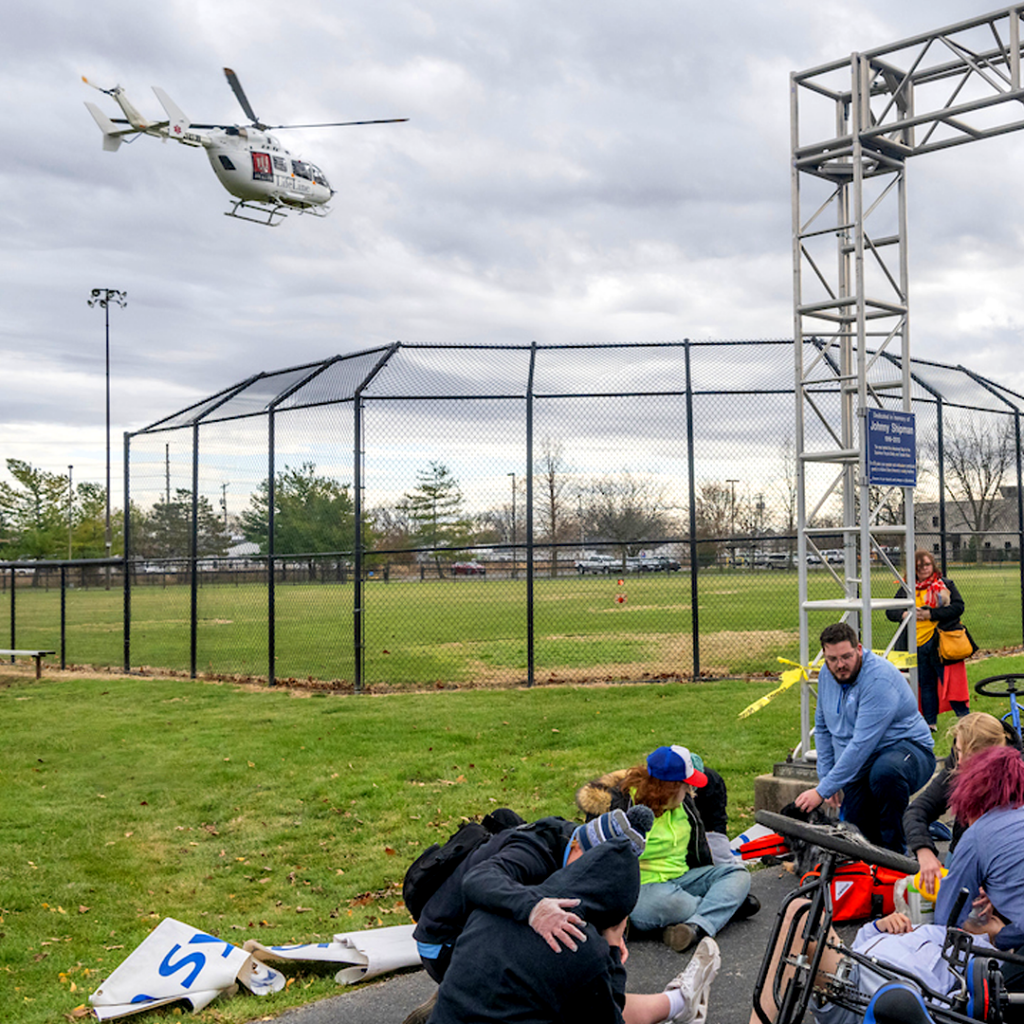 helicopter flies over simulation of athletic trainers assisting patients in a bicycle accident