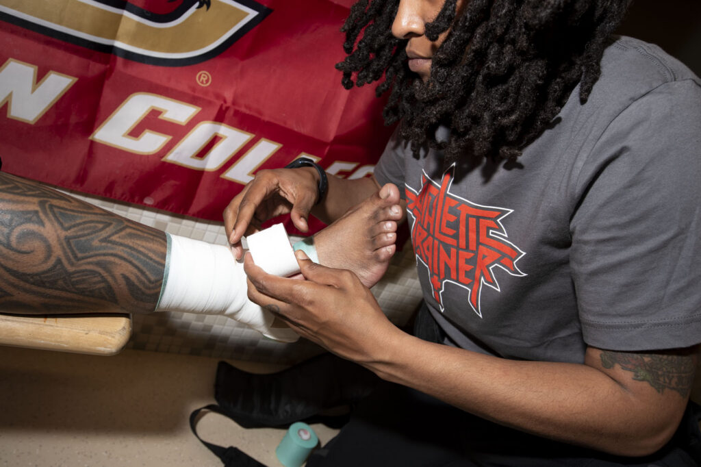 Athletic Trainer Asia McCants tapes an ankle before a football game.