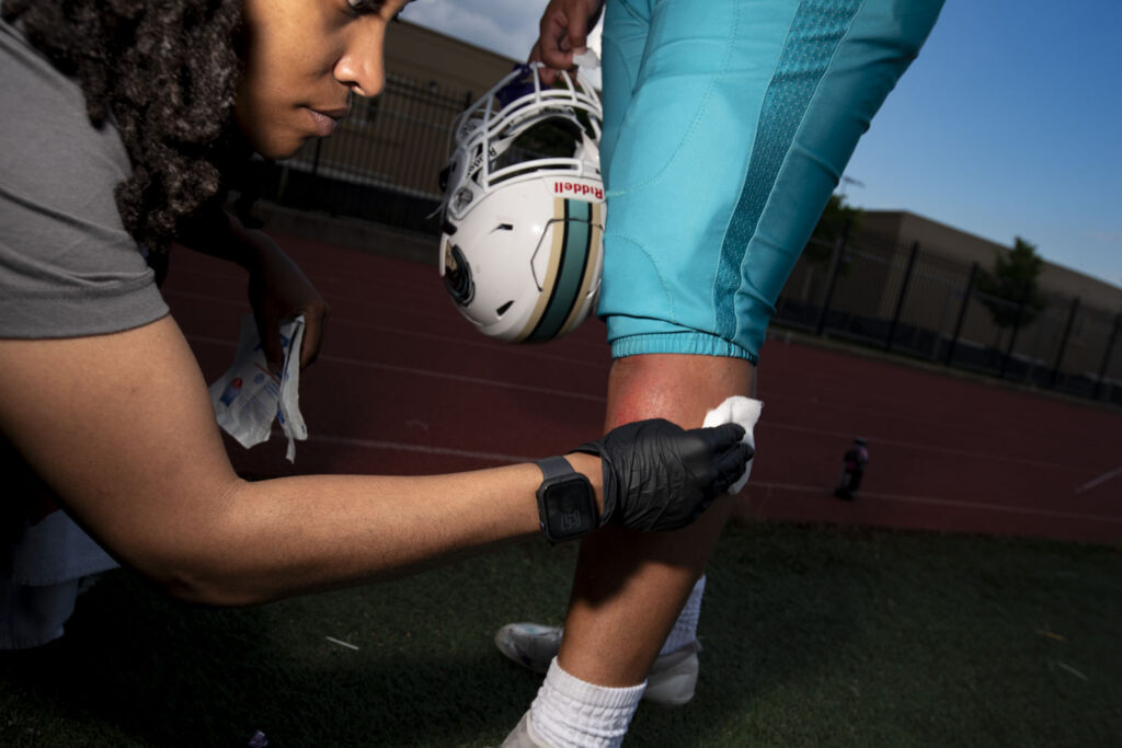 Athletic Trainer Asia McCants works on a football player's injury on the sideline of a football game.