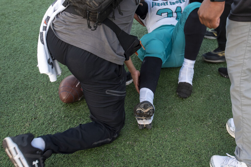 Athletic Trainer Asia McCants evaluates a football player's injury on the field of a football game.