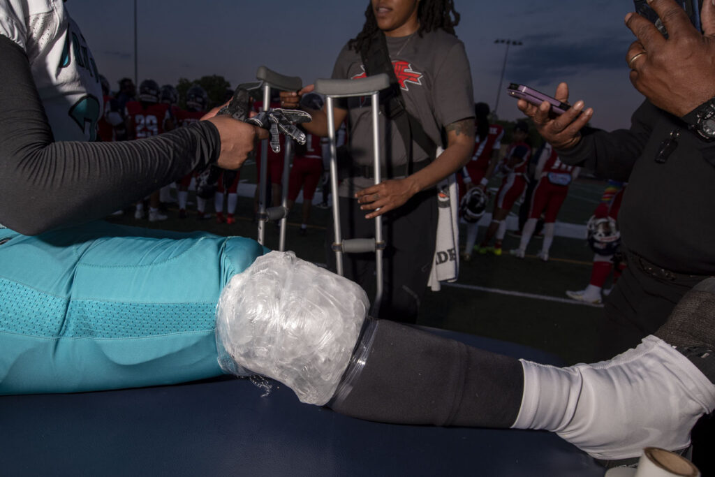 Athletic Trainer Asia McCants brings an injured football player crutches on the sideline of a football game.
